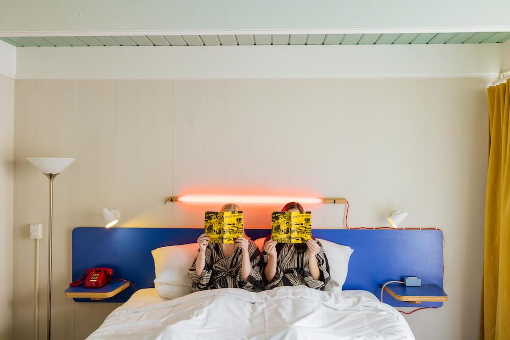 Two guests in bed reading the Zine at The Phoenix Hotel