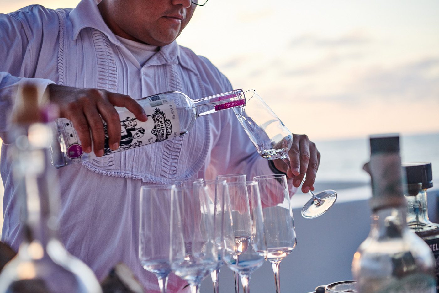 Man pouring mezcal in various wine glasses