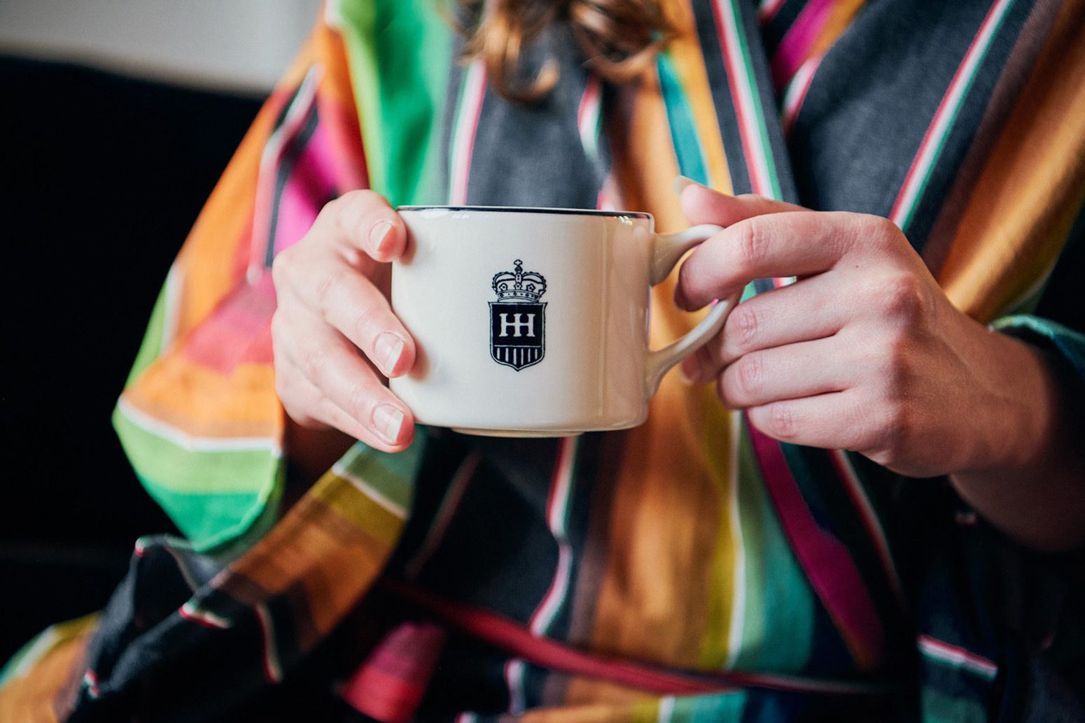Women in hotel havana robe holding a mug with HH and the crest on it